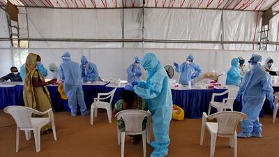 A healthcare worker takes a swab from a woman for a rapid antigen test at a check-up point in Ahmedabad, India. Reuters