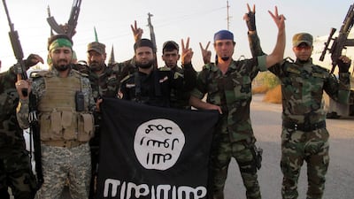 Members of Iraqi Shiite militia Kataib Hezbollah flash the victory sign while holding a captured ISIS flag in southern Iraq, in 2014. EPA
