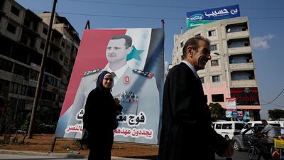People walk in front of a billboard with a picture of Syrian President Bashar Al Assad in Homs, Syria. Reuters