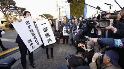 Lawyers for evacuees who were forced abandon their homes near the Fukushima nuclear plant hold signs on March 17, 2017, that read “partially won a case,” right, and “the government is liable” in front of the district court of Maebashi, north of Tokyo. Fumine Tsutabayashi / Kyodo News via AP