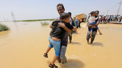 Residents of Al Jazeera state south of the Sudanese capital Khartoum wade through flood water in late August. Reuters