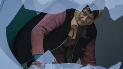 A woman cleans broken glass from a staircase in an apartment building damaged by bombing in Kyiv, Ukraine. AP