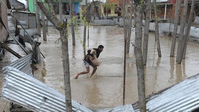 A resident carries a sheep through waters in a neighbourhood of Srinagar on March 30, 2015. At least 15 people have been buried by mudslides and hundreds more have had to flee their homes after heavy rain triggered flooding in Indian Kashmir. Rouf Bhat/AFP Photo