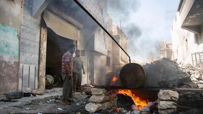 Syrians Mohammed Ibrahim, left, and Abu Majd distill melted plastic in a barrel as part of a refining process to produce fuel in Aleppo’s rebel-held eastern district of Sakhur on September 10, 2016, days before Abu Mahjd and another colleague were burned to death when a barrel exploded during the melting process. Karam Al Masri/ AFP