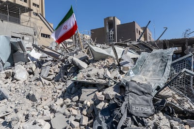 An Iranian flag is planted in the rubble of a police station, damaged in air raids on Tehran. Getty Images