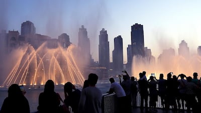 Tourists take photos of the fountain at the Burj Khalifa lake in Dubai. The travel and tourism sector continued to expand in May. Satish Kumar / The National