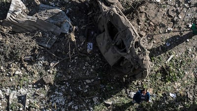 A woman stands next to the bombed wreck of a car in Kyiv. AFP