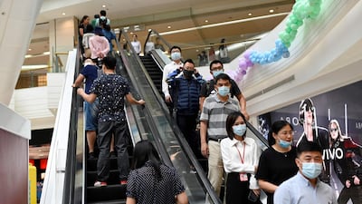 People take an escalator at a mall in Beijing. Coronavirus-ravaged economies across the Asia Pacific will make a 'swoosh-shaped' recovery next year, according to the Asian Development Bank forecast. AFP
