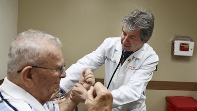 A cardiologist checks the arm strength of a patient during a consultation. Getty Images