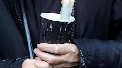 A mourner waiting for the funeral procession of John Hume holds a candle outside St Eugene's Cathedral. Reuters