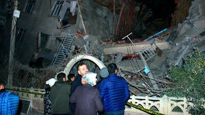 People look at a collapsed building in Elazig city centre in the eastern Turkey on Friday AP