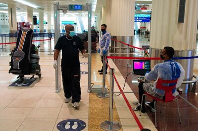 A passenger wearing a mask due to the coronavirus pandemic passes through a temperature screening at Dubai International Airport's Terminal 3. Jon Gambrell / AP