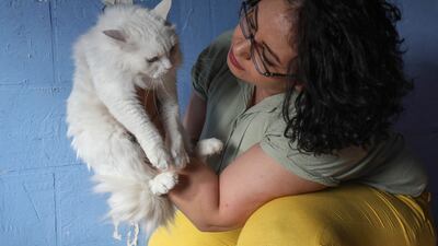 Amal Amro, the Palestinian-Syrian owner, plays with a cat at 'Amal Pets Hotel' in Arbil, the capital of Iraq's northern Kurdish autonomous region, on August 24, 2022. (Photo by SAFIN HAMED / AFP)