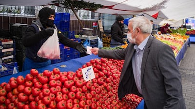 A man buys tomatos at an outdoor market in Istanbul. Bloomberg