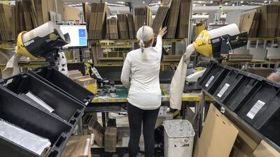 Workers prepare customer orders for dispatch as they work around goods stored inside an Amazon.co.uk fulfillment centre in Peterborough. AFP