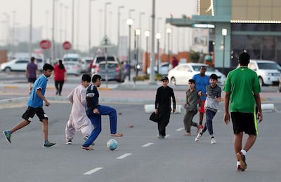 Children play football in a car park as the sun sets over Mussaffah. Pawan Singh / The National