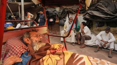 A rickshaw driver sleeps as other labourers chat before starting work early in the morning in the old quarter of New Delhi, India. AP