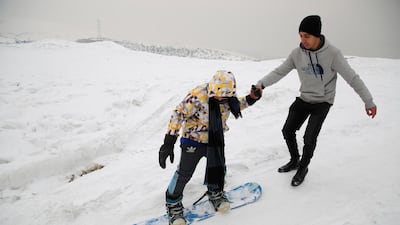Zahra Hakimi, a member of the minority Hazara ethnic group, tries snowboarding with a trainer on the snow-covered hillside known as Kohe Koregh. AP