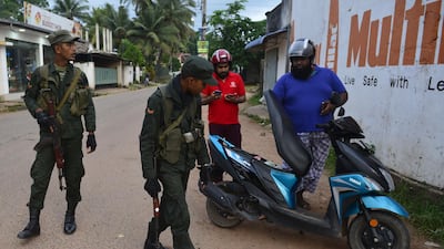 Security personnel inspect a motorcycle at a checkpoint on a roadside in Minuwangoda. AFP