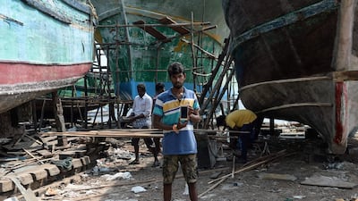 Indian carpenter Deepan Raj, 25, poses with his smartphone at a fishing vessel dockyard at Kasimedu harbour in Chennai. AFP