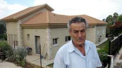Abu Arab, a refugee from the destroyed Palestinian village of Saffuriya, stands in front of homes being built for Jews on land that was once his parents.