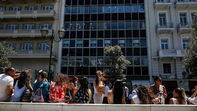 People speak on their phones as they stand outside the building they work in with the Greek Parliament in the background, after a strong earthquake hit near the Greek capital of Athens, Friday, July 19, 2019. The Athens Institute of Geodynamics gave the earthquake a preliminary magnitude of 5.1 but the U.S. Geological Survey gave it a preliminary magnitude of 5.3. The Athens Institute says the quake struck at 2:38 p.m. local time (1113 GMT) about 26 kilometers (13.7 miles) north of Athens. (AP Photo/Petros Giannakouris)