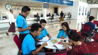 Two car owners (right) purchase vehicle insurance from a private insurance company in Yangon. Romeo Gacad / AFP
