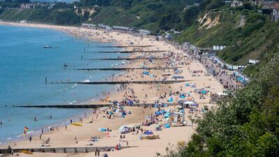 People enjoy the sunny weather on Durley Chine Beach in Dorset. PA