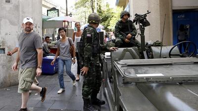 Foreign tourists walk past soldiers at the Ratchaprasong intersections in Bangkok. Rungroj Yongrit / EPA