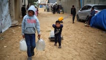 Displaced Palestinian children carry water canisters at the Nuseirat refugee camp in central Gaza. AFP