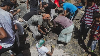 Jamal Mohammed hands friends a parcel of shuwah meat. About 40 burlap sacks of shuwah are cooked in the communal pit, each marked with a metal object to identify its owner. Ania James for The National