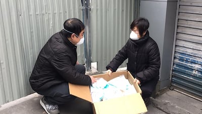 A volunteer with a disability group who is deaf, shows Cui Jing (R) distributing masks to help with the COVID-19 coronavirus outbreak in Wuhan in China's central Hubei province. AFP