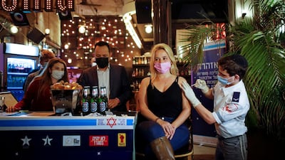 A woman is immunised against Covid-19 as part of a Tel Aviv municipality initiative offering a free drink to people having the vaccine shot.