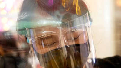 A cashier wears a face shield behind plastic protection as she works in a supermarket in Bangkok, Thailand. Reuters