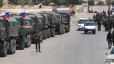 Syrian and Russian soldiers wait at the entrance of the Wafideen Camp for the arrival of buses carrying Jaish Al Islam fighters and their family members evacuated from the Eastern Ghouta town of Douma, on April 12, 2018. Youssef Karwashan / AFP