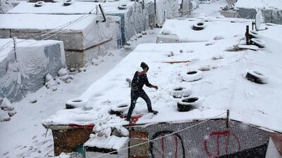 A Syrian boy throws snow from the top of his tent at a refugee camp in Deir Zannoun village, in the Bekaa valley, east Lebanon on Wednesday, January 7. Hussein Malla / AP Photo
