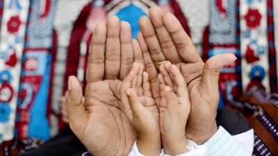 A Muslim father assists his son during Eid Al Adha prayers near a Masjid in Calcutta, eastern India. EPA