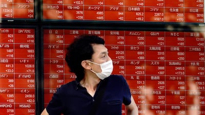A man stands in front of an electronic stock board showing Japan's Nikkei 225 index at a securities firm in Tokyo. The recent surge in new cases, particularly in the US, highlights that volatility is set to stay in the markets, says Gaurav Kashyap. AP