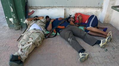 Libyan rebel fighters rest after an attack by pro-Gaddafi forces at a Gaddafi army women's officer training center in Tripoli August 22, 2011. Ongoing fighting with snipers and other pro-Gaddafi forces has prevented the rebels from gaining control of the ???