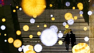 A couple under an umbrella walk amid Christmas illuminations in Tokyo. Many shopping malls, leisure facilities and streets start competing illuminations attracting people for Christmas and New Year selling season in Japan. Kimimasa Mayama / EPA