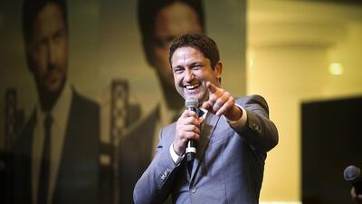 Scots actor Gerard Butler has a joke with a fan who holds aloft a Saltire, the Scottish flag, during his appearance at Dubai Mall on Friday night. Lee Hoagland / The National