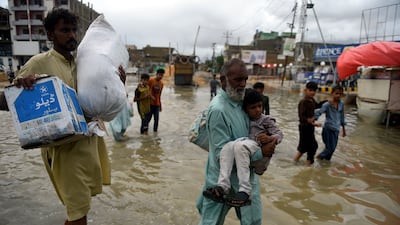 People wade through a flooded street after a rainstorm. AFP