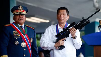 Philippine President Rodrigo Duterte, right, jokes to photographers as he holds an Israeli-made Galil rifle in Manila in April. AP