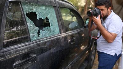 A photographer at work next to a damaged car in the aftermath of a rocket attack in central Kabul, Afghanistan. EPA