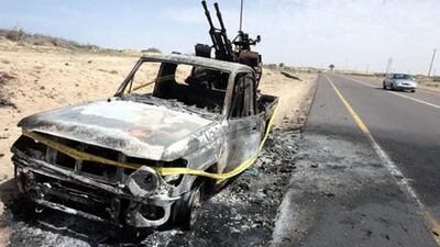 A burned-out vehicle on the side of a road leading to Brega.