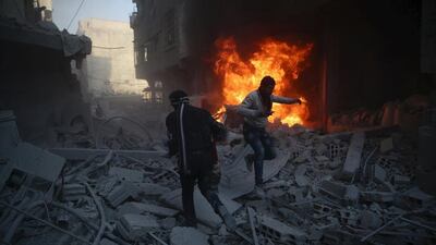 Residents move amidst rubble near a burning vehicle in a site damaged from what activists said was shelling by forces loyal to Syria's President Bashar Al Assad in the town of Douma, eastern Ghouta in Damascus on December 30, 2015. Bassam Khabieh / Reuters