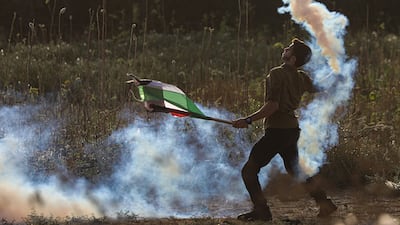 A Palestinian protester throws a tear gas canister back at Israeli troops on the eastern border of the Gaza Strip on Wednesday. EPA