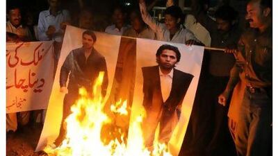 Angry Pakistani fans burn posters of Salman Butt, left, and Mohammad Asif in Multan.