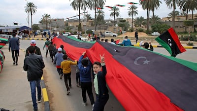 Children carry a Libyan flag as the country marks the 10th anniversary of the uprising that toppled Qaddafi in 2011. AFP