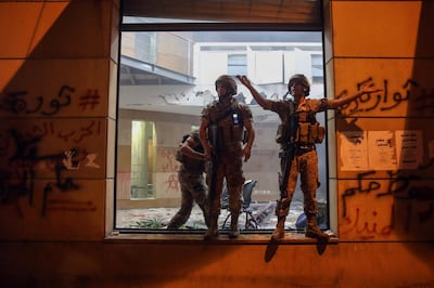Lebanese army soldiers stand guard by a shattered window inside the Lebanese Banks Association which had been a target of enraged protestors. Bloomberg